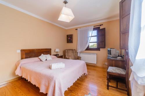 a bedroom with a bed and a chair and a window at Casa Rural De Cabrera in Urrez
