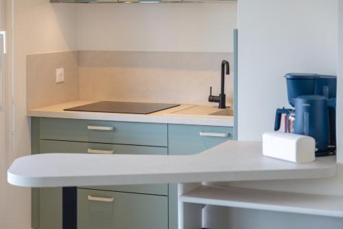 a kitchen with blue cabinets and a sink at La pause iodée Studio -grand balcon in Concarneau