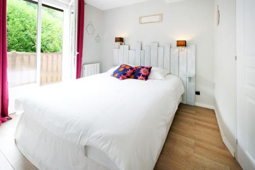 a white bedroom with a large white bed and a window at Appartement, 2 à 4 pers in Urrugne