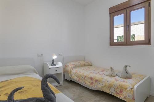 a white room with two beds and a window at Casa Sofia in Conil de la Frontera