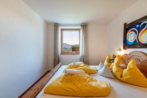 a bedroom with two beds with yellow sheets and a window at Gunzhof in Kastelruth