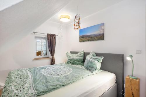 a bedroom with a bed with a green comforter and pillows at Ferienwohnung zum Heubalken in Schmallenberg