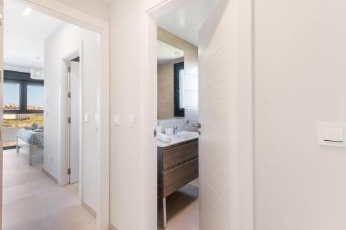 a white bathroom with a sink and a mirror at Los Flamencos in Isla Canela