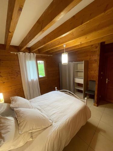 a bedroom with a white bed in a room with wooden walls at Le Chalet de Noblat in Saint-Léonard-de-Noblat