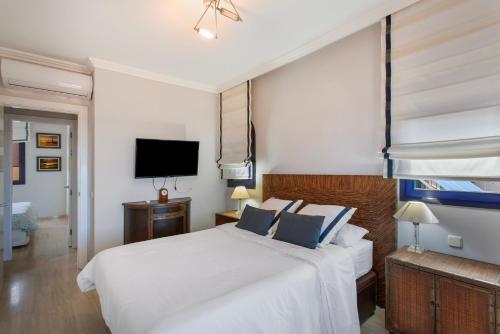 a bedroom with a white bed and a flat screen tv at Bahia Meloneras Luxury Duplex in Maspalomas