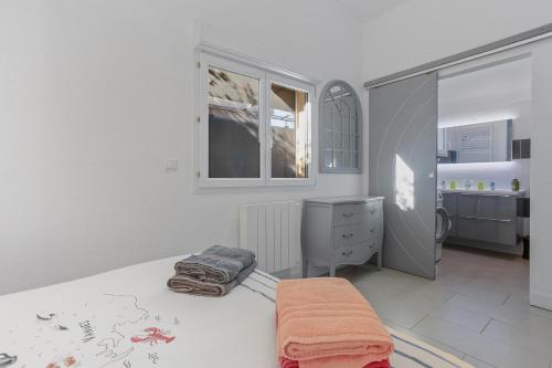 a white bedroom with a bed and a dresser at Les Sables in Bormes-les-Mimosas