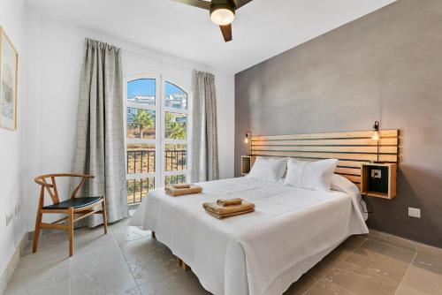 a bedroom with a white bed with a chair and a window at Casa Maria Luisa in Manilva
