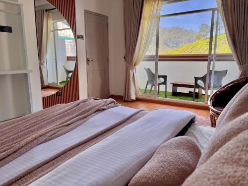 a bedroom with a bed and a large window at Seeming Lodge in Nuwara Eliya