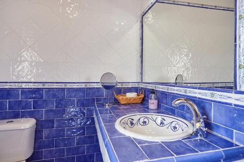 a blue tiled bathroom with a sink and a toilet at Casa Calera in Arbuniel
