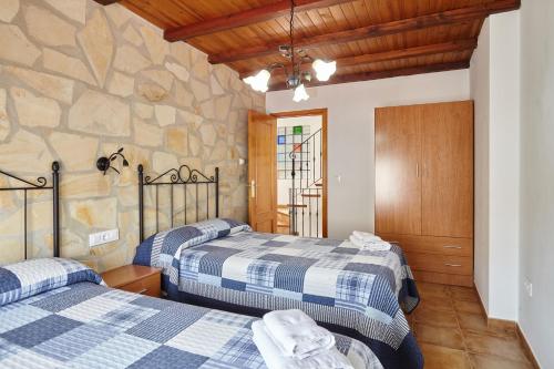 two beds in a room with a stone wall at Casa Calera in Arbuniel