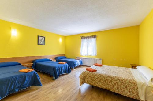 three beds in a room with yellow walls at El Calderillo in Burgohondo