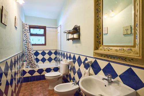 a blue and white bathroom with a toilet and a sink at Rivero Rural in Rivero de Posadas