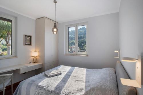 a white bedroom with a bed and two windows at Villa Vallegrande in Ospedaletti