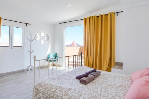 a bedroom with a bed and a yellow curtain at Ático deluxe Corralejo centro in Corralejo