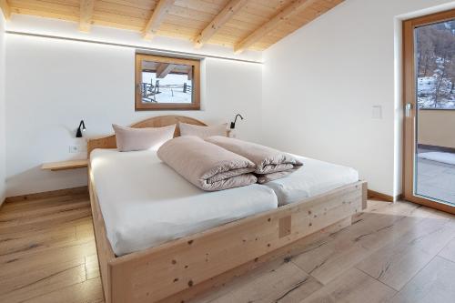 a bed with white sheets and pillows in a room at Hof Am Egg in Malles Venosta