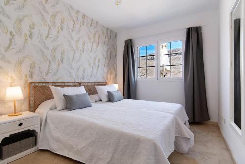 a bedroom with a bed with white sheets and a window at Mangueros Suite 36 Puerto de Mogán in Puerto de Mogán