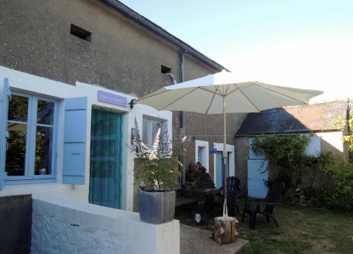 a patio with an umbrella in front of a house at Maison Lavande in Blismes