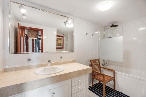 a bathroom with a sink and a mirror and a chair at Casa Papaya in El Médano