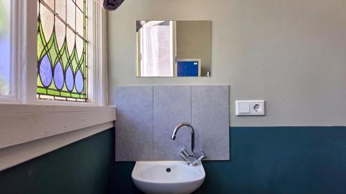 a bathroom with a sink and a mirror and a window at Hostel Cosmos Amsterdam in Amsterdam
