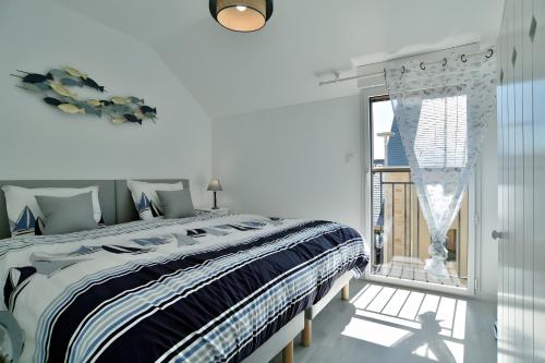 a white bedroom with a large bed and a window at Maison Les Flots De Port-mer in Cancale