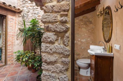 a bathroom with a stone wall and a toilet at Siglo 16 Denia in Denia