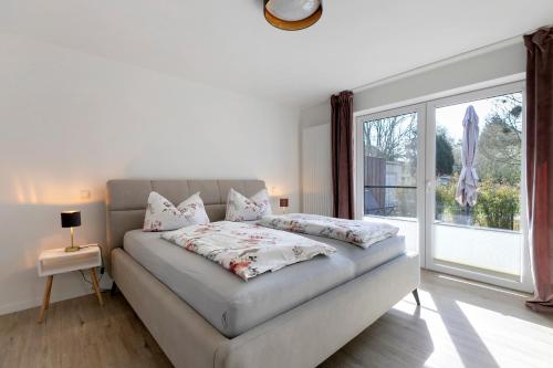 a white bedroom with a bed and a large window at Ferienwohnung Emilia in Garding