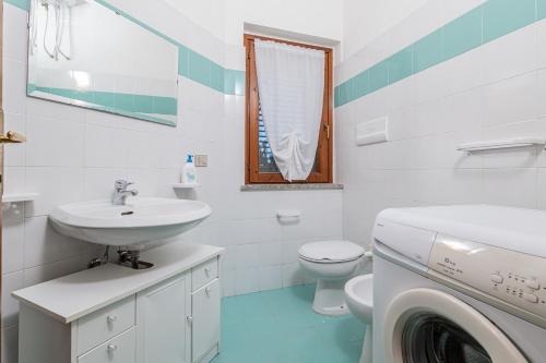 a white bathroom with a sink and a washing machine at Domus Dejana in San Teodoro