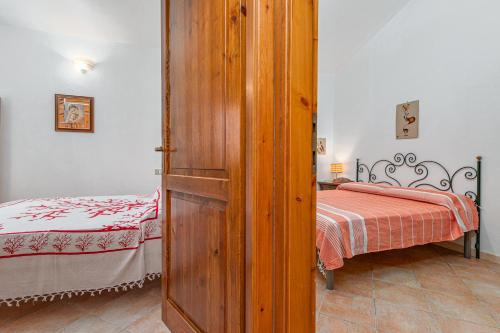 a small bedroom with a bed and a wooden door at Domus Dejana in San Teodoro