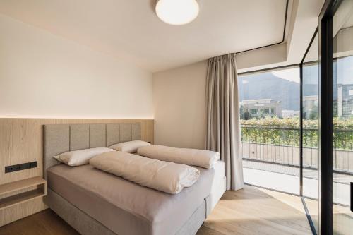 a bedroom with a bed and a large window at Trianglhof surrounded by vineyards in Bolzano