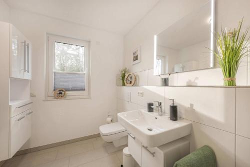 a white bathroom with a sink and a toilet at FeWo Meerzeit Bernsteinquartier in Loddin