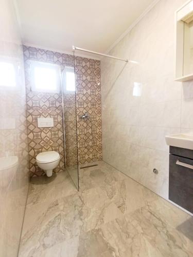 a bathroom with a toilet and a glass shower at Kucica na Drini MINJA in Višegrad