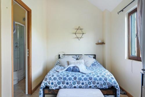 a bedroom with a bed with a blue and white comforter at Gîte Chemin Des Hêtres in Armaillé