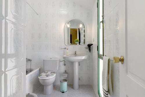 a white bathroom with a toilet and a sink at Colina Verde Maspalomas in Maspalomas