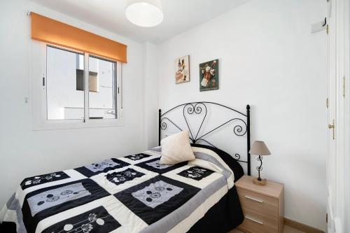 a bedroom with a black and white bed and a window at Apartamento Merce in Rota