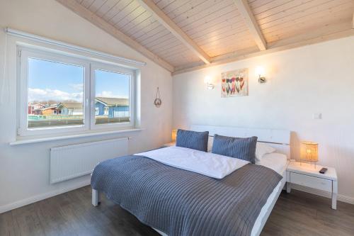 a bedroom with a large bed with a window at Ferienhaus Stockente in Dagebüll