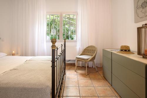 a bedroom with a bed and a chair and a window at Villa Polina in Capdepera
