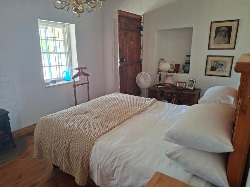 ein Schlafzimmer mit einem Bett mit weißer Bettwäsche und einem Fenster in der Unterkunft Van Wyks Hartshuis in Sutherland