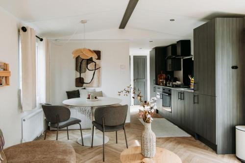 a kitchen and living room with a table and chairs at 't Veluws Nest - Knus Chalet Veluwe - Hoenderloo, Honden welkom in Hoenderloo