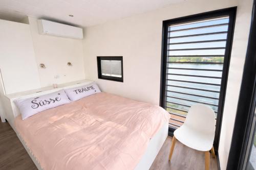 a bedroom with a bed and a chair and a window at Floatinghouse Bakerman in Zehdenick