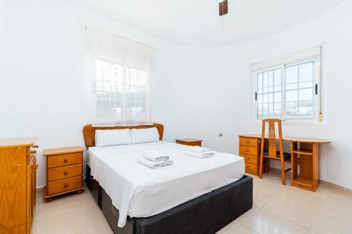 a bedroom with a bed and a desk and two windows at Chalet del Lago in Torrevieja