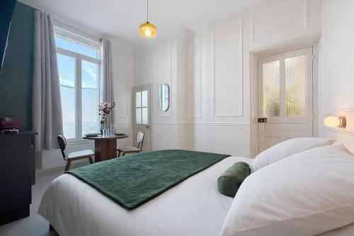 a bedroom with a white bed with a green blanket on it at Le Studio du Chateau in Bréviandes