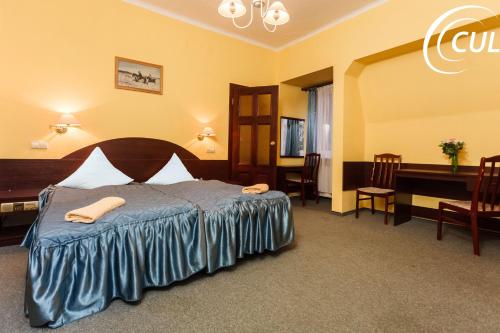 シュクラルスカ・ポレンバにあるOśrodek Wypoczynkowy Rzemieślnikのベッド、テーブル、椅子が備わるホテルルームです。
