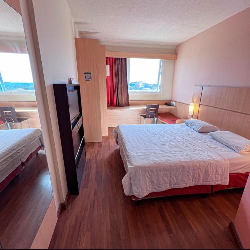 a hotel room with two beds and a window at Samba Itaboraí in Itaboraí