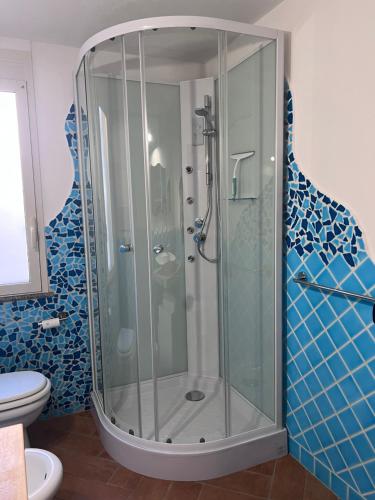 a glass shower in a bathroom with blue tiles at Appartamento Blue in Cala Gonone