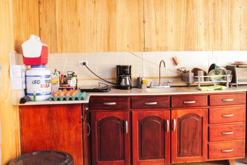 a kitchen with wooden cabinets and a sink and a counter at Hostal Casa Las Flores in Masaya