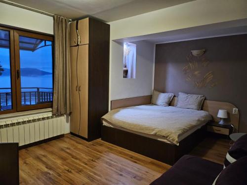 a bedroom with a bed and a large window at Guest house Lidia in Tsigov Chark