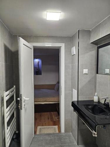 a small bathroom with a sink and a bedroom at Guest house Lidia in Tsigov Chark