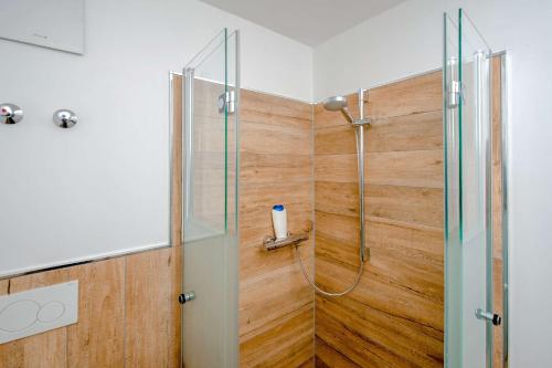 a bathroom with a shower with a wooden wall at Ferienwohnung Heuschober in Neuendorf am See
