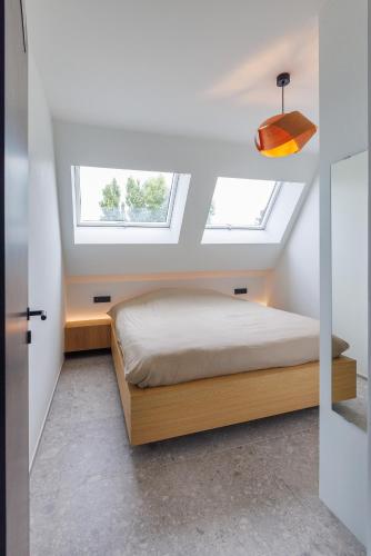 a bedroom with a bed and two windows at Apartment L'O Reine, B&B in Sint-Pieters-Leeuw