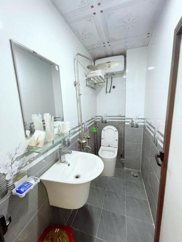 a bathroom with a sink and a toilet and a mirror at Sơn Tùng Hostel in Cat Ba